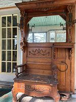 Front view of carved oak hall tree with mirror and seat