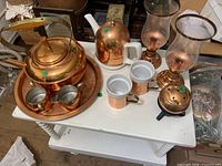 All ten copper and mixed material kitchenware and decor pieces grouped on table