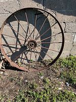 Full view of metal wagon wheel leaning against wall