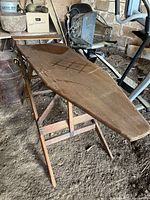Full view of wooden folding ironing board opened on legs showing overall design and wear