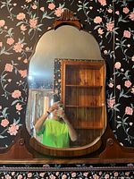 Mirror on wall showing arched wooden frame with carved crest