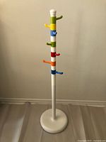 Full view of white coat tree with multicolor hooks