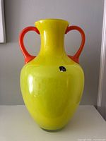 Front view of yellow glass vase with orange handles showing overall form, size and color