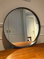 Front view of round mirror on table, showing full reflective surface and frame