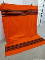 Full view of orange blanket with black stripes displayed hanging