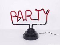 Front view of red neon "PARTY" lamp on black base, unlit