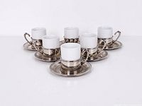 Front view of six assembled espresso cups in holders on saucers