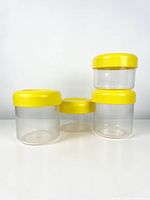 Front view of four clear plastic canisters with yellow lids, two stacked