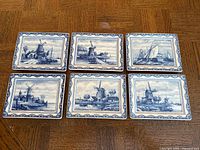 Front view of six rectangular Delftware trays showing blue-and-white scenes