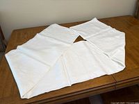White Irish linen tablecloth unfolded on wooden table