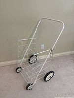 Perspective view of white wire utility cart with tubular handle and four wheels