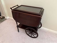 Side view of mahogany tea wagon with drop leaves closed and large spoke wheels