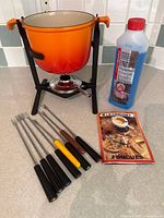 Full view of fondue set with pot, stand, burner, forks, fuel, booklet