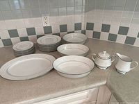 All pieces grouped on countertop showing plates, platter, bowls, sugar and creamer
