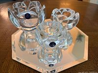 Three crystal lotus candle holders of varying sizes on octagonal mirror tray