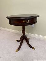Full view of table showing drawer front, pedestal, legs, brass caps