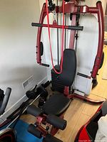 Front view of Best Fitness home gym with seat, chest press arms, rope attachment, accessories on floor
