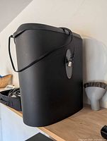 Side view of black paper shredder showing attached power cord and oval viewing window