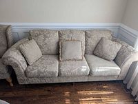 Front view of cream damask sofa with three throw pillows