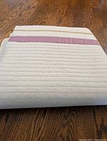 Folded quilt showing ivory surface with purple horizontal band
