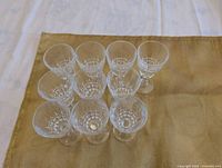 Top view of ten small stemmed crystal glasses showing geometric cut pattern