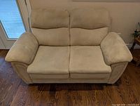 Front view of tan suede loveseat showing seat and back cushions