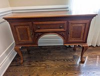 Front view showing carved details, inlay panels, drawer, doors, legs