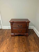 Front view of wooden nightstand showing two drawers and carved details