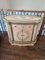 Front view showing floral wreath, drawer, double doors