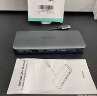 Top view showing Mokin hub, HDMI, USB-C PD, two USB-A ports, instruction manual.