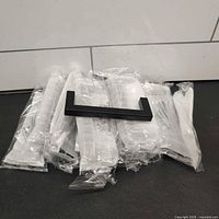 All thirteen packaged satin black drawer pulls with one unpackaged example