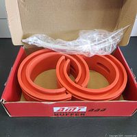 pair of red rubber coil spring buffers inside open AMT box with plastic sleeve