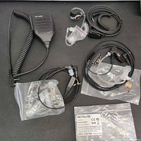 All four accessories laid out: shoulder mic plus three bagged earpiece headsets