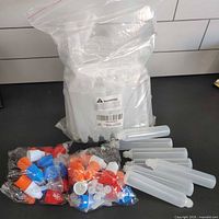 Factory bag containing multiple translucent 30 ml pen-style bottles, separate bag of coloured caps and loose sample bottles