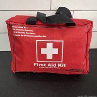 Front view of red Songwin first aid kit bag showing white cross logo