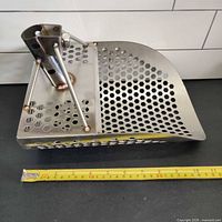 Side profile of stainless steel sand scoop with tape measure indicating length