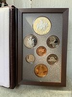 Open case showing reverse designs of seven proof coins