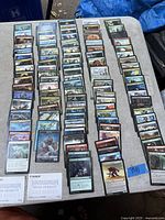 Full view of six orderly rows of loose MTG cards on table; two Kamigawa art cards visible