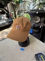 Front and side view of brown Carhartt baseball cap on stand