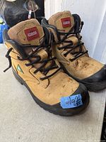 Side view of both boots showing leather uppers, laces, CSA green triangle, branding, toe caps