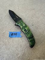 Knife fully folded out on surface showing black blade and wolf graphic handle