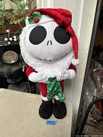 Front view of Jack Skellington Santa plush standing on table