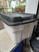 Side view of white Rubbermaid tote with black lid