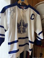 Front view of signed CCM Toronto Maple Leafs boys L jersey showing crest, captain "C" patch, and autograph