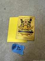 Front view of gold metal Pikachu Mega Ampharos card with yellow sleeve