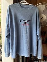 Front view of light blue Tommy Hilfiger crew-neck sweatshirt on hanger