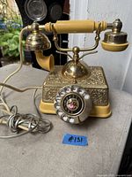 Full view of brass French style rotary phone showing handset, base, rotary dial and cord