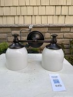 Front view of bronze two-light vanity sconce with white glass shades