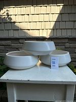 Three ceramic planters stacked on small table outdoors