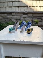 All four ceramic shoe figurines grouped on table